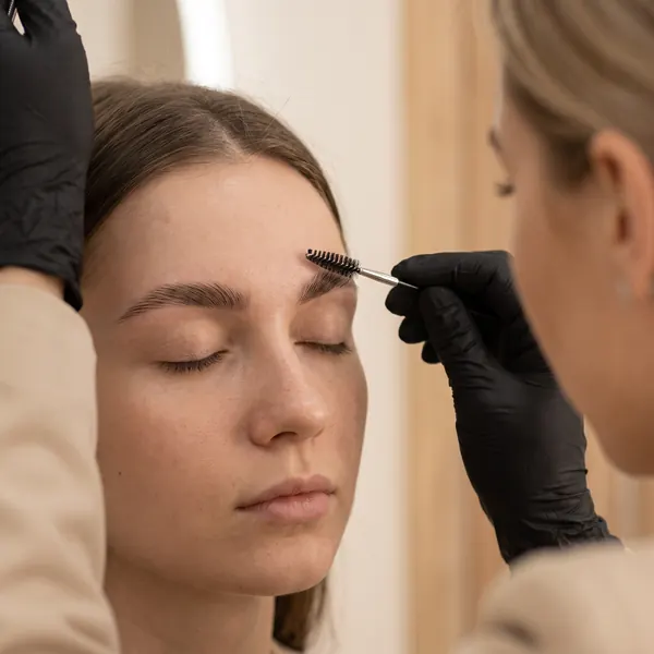 Brow artist brushing up an eyebrow with a spoolie during lamination