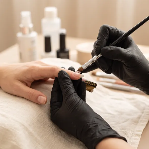 Technician sculpting a hard gel nail extension on a nail form